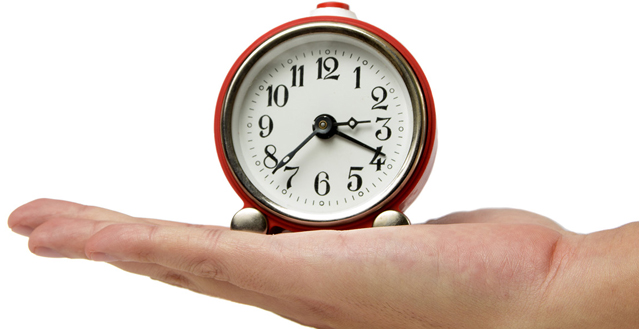 Image of a person's hand holding a clock denotes the phrase "time on your hands."