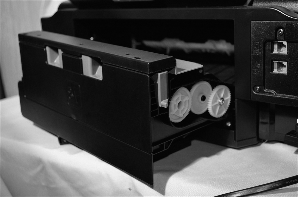 A photograph of a duplexing assembly in an inkjet printer is shown. The tray which contains a few rollers on the side is opened.