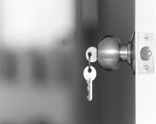 A photograph of a conventional lock with a key in the door handle.
