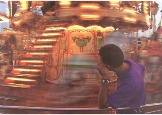 With the camera set to a shutter speed of 1/8 second, I used a picnic table as an impromptu tripod a keep the bored ride attendant sharp the spinning merry-go-round blurred itself. Exposure at 1/8 second, f/8.