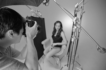 Fashion photographer Tri Huynh photographs a model in the studio with his camera tethered to a nearby computer.