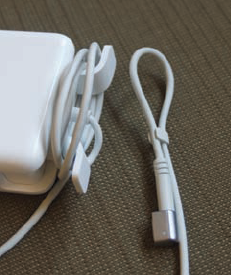 This laptop power adapter includes brackets for winding the power cord, as well as a small clasp for securing the cord's end.