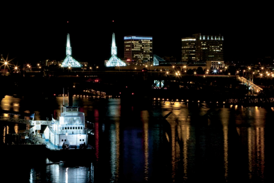 A tugboat sits idle along the bank of the Willamette River with the Portland skyline in the background in this nighttime shot. Exposure: ISO 3200, f/22, 2 seconds.
