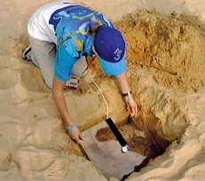 Figure 9.9 A contact microphone being buried in the sand at a long jump competition. The microphone picks up the vibration of the landing.