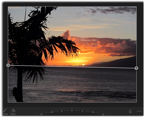 If iPhoto finds a horizon in your photo, it displays a line on top of it, as shown here. To have iPhoto straighten the photo automatically, tap the curved arrow at the right end of the line. To delete the line, tap the X on the left end instead.