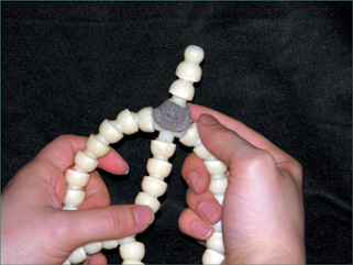 Break off three beads from another doll armature and attach them to the top with epoxy putty for a neck piece.