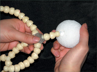 Gouge a hole into a Styrofoam ball with the plastic neck piece so that it creates a hole exactly the right size.