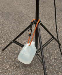 Attach a filled water jug to a light stand with a bungee cord when shooting outdoors with umbrellas or soft boxes. The weight of the jug at the bottom of the stand adds stability. Copyright © Steve Weinrebe