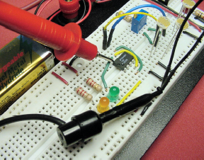 Testing the comparator's positive voltage pin with the multimeter test probe tip