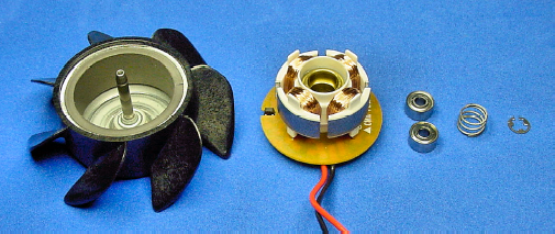 Guts of a brushless motor for a fan: (left to right) rotor with permanent magnet, stator with armature, pair of bearings, compression spring, and a retaining ring