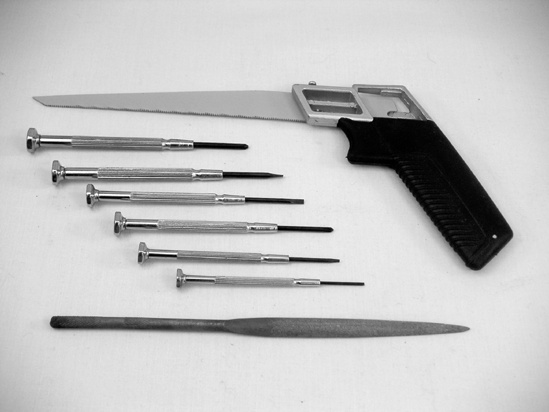 Jeweler’s screwdrivers (center), a tapered half-round file (bottom), and a hacksaw (top)