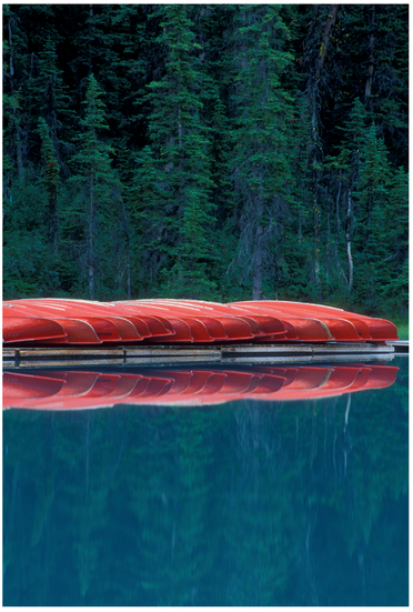 FIGURE 11 Early in the morning, this Canadian mountain lake was very calm, almost waiting for people to come enjoy it. To convey a sense of serenity and place, I found these canoes lined up. We know that canoeing is a sport, so there’s a sense of anticipation seeing them waiting to be used, and because there are so many canoes, we can infer that a lot of people will be active in this lake. The reflection on the still water and blue colors add a sense of serenity, and the red in the canoes adds visual intensity. The overall intensity is lower, though, as this image has a calm story.