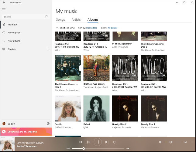 This screenshot shows the Groove Music app, with a search box and menu bar on the left, cover art for a dozen albums in the center, and playback controls along the bottom.