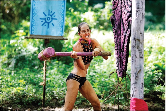 Image of the author Janine Allis, who is striking a hammer on the wooden pole. 