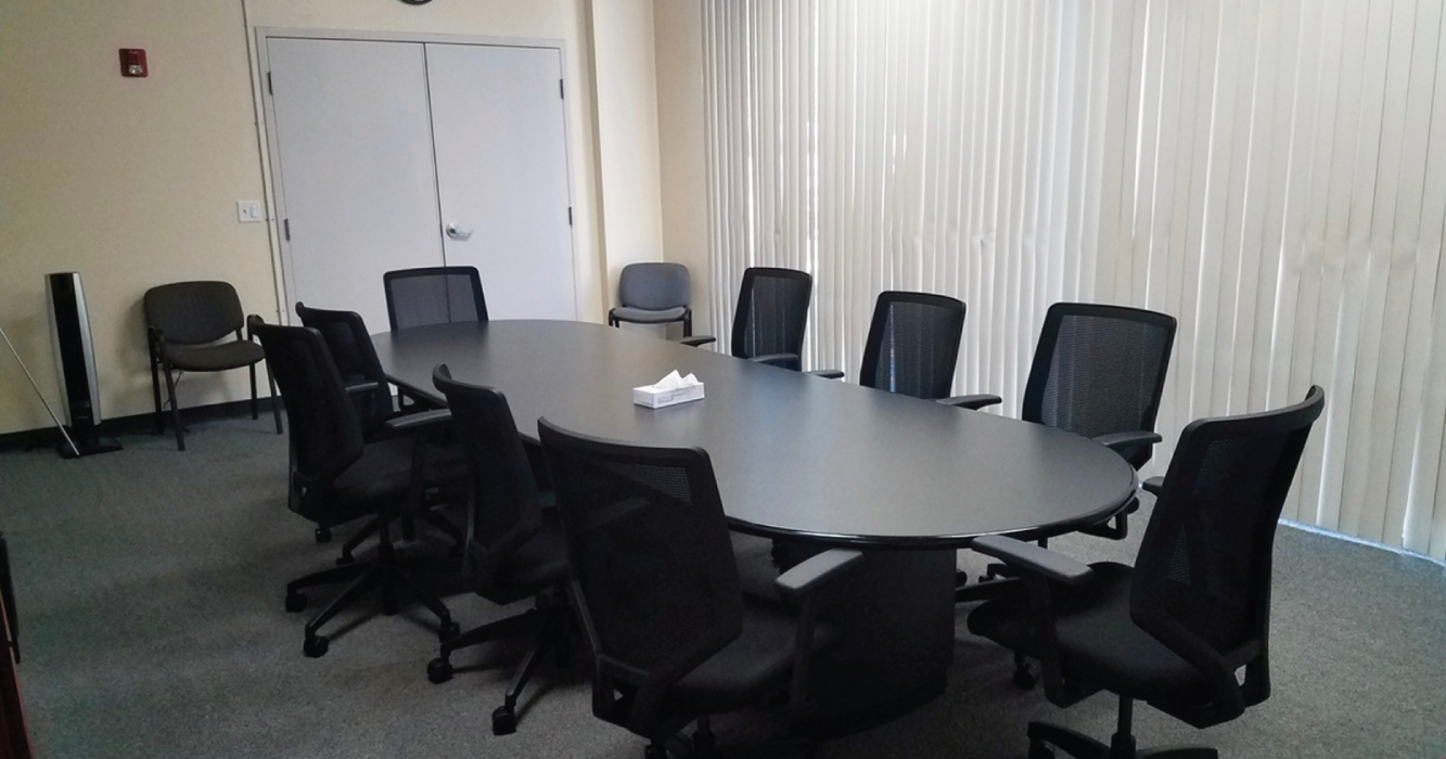 Photograph of a conference room - a long room with an oblong table and chairs where 10 people can be seated at a time.