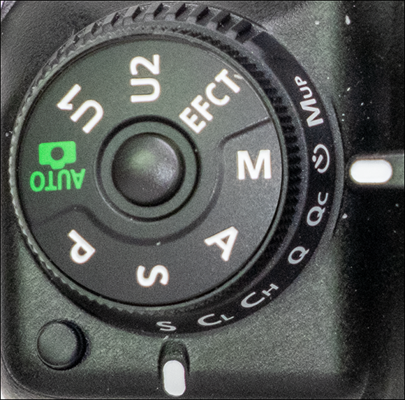 Image of the mode dial lock release button to rotate the mode dial to M for manually exposing the image.