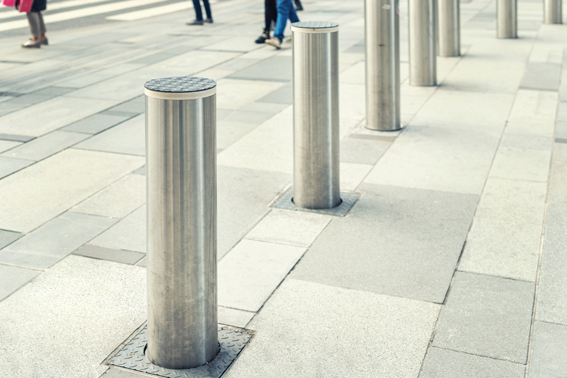 A photograph shows a concrete platform area with several bollards placed along the edge.