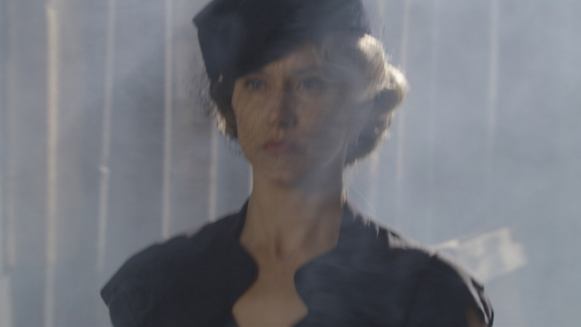 A screenshot of the clip in the lady walking sequence showing the picture of a lady against a smoky background.
