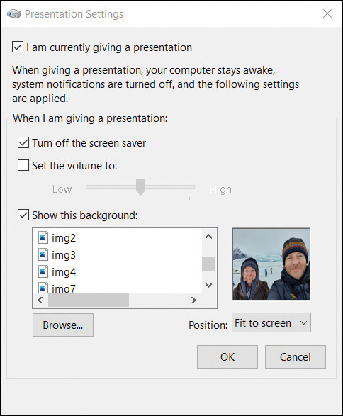 This screenshot shows the Presentation Settings dialog box. There are four settings managed by checkboxes of I am Currently Giving a Presentation (enabled), Turn Off The Screen Saver (enabled), Set The Volume To (not enabled) and Show This Background (enabled). The Show This Background setting includes a list of images that can be selected and a Browse button. To the right of the list of images an image thumbnail is displayed and a drop box to manage the position of the image is set to Fit To Screen