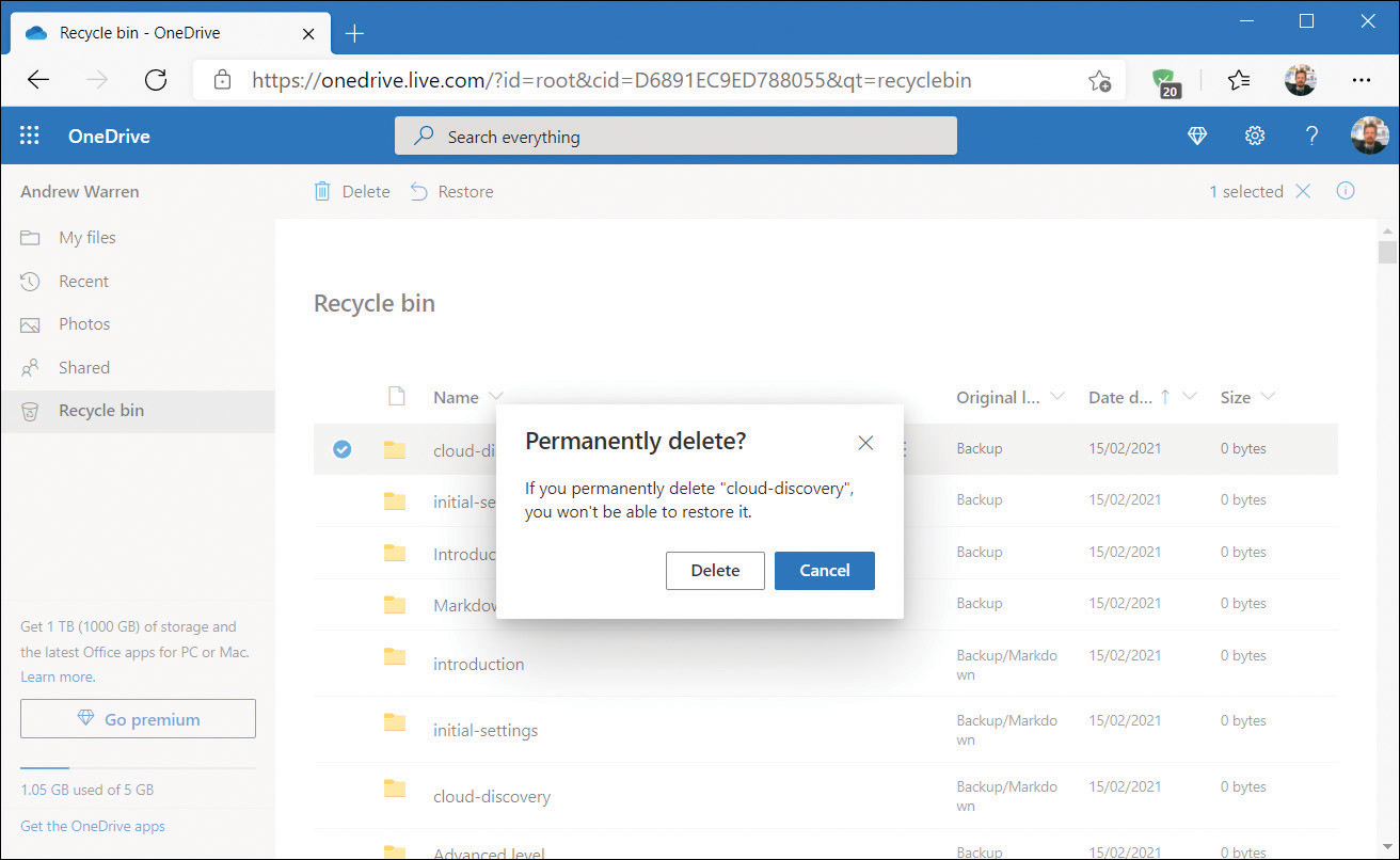 A screenshot of the OneDrive.com Recycle Bin, with the Permanently Delete dialog box in focus. This dialog box is advising you that if you permanently delete the selected items you won't be able to restore them. A Delete and a Cancel button are available.