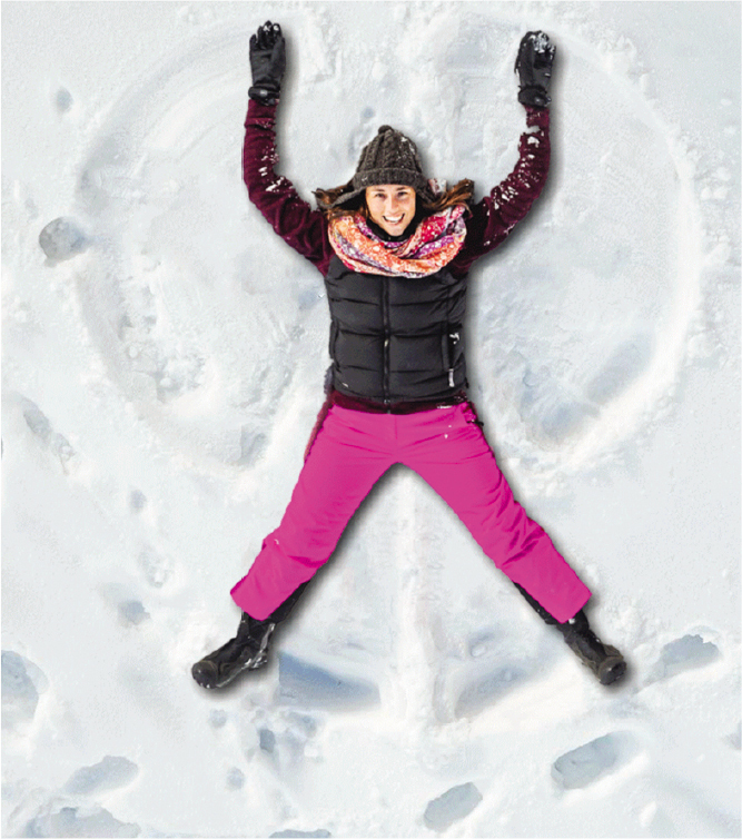 A woman lying flat on her back moving her hands and legs to make a snow angel.