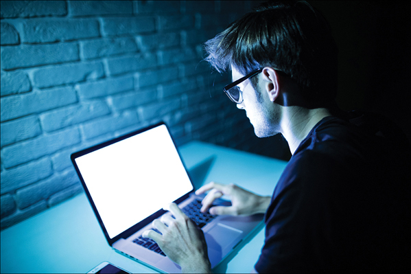 A photograph shows a man working on a laptop computer.