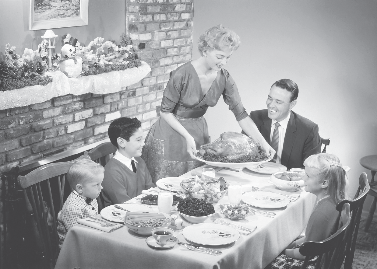 Photograph shows a family having a meal.