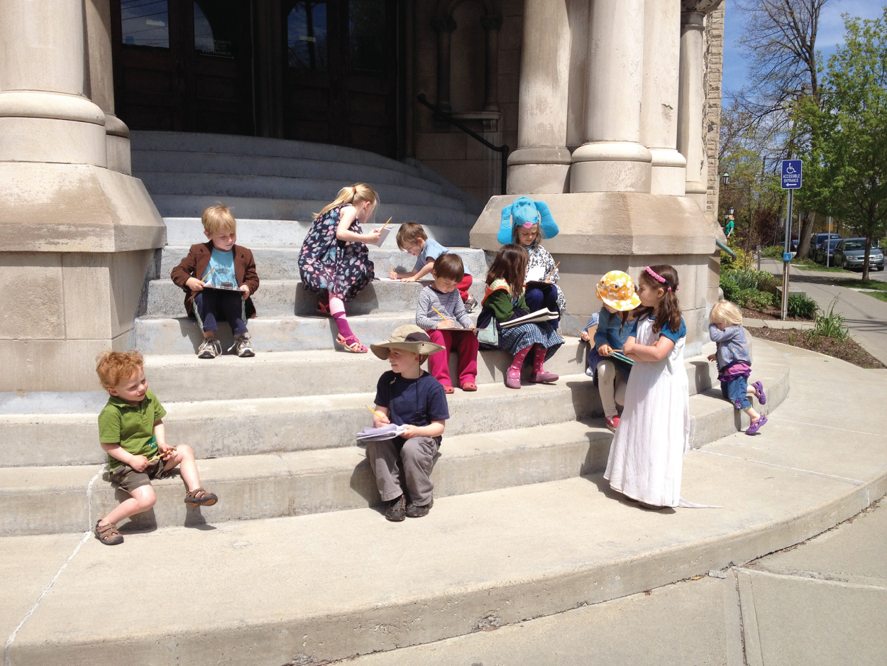 Photo depicts students using the steps of a church for writing in the neighborhood.