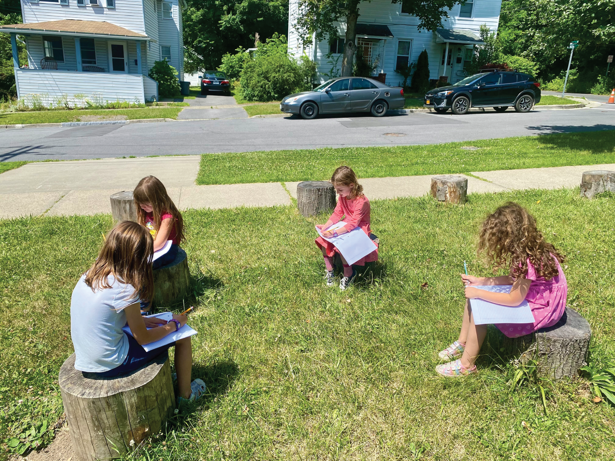 Photo depicts group work while sitting on log stump seats