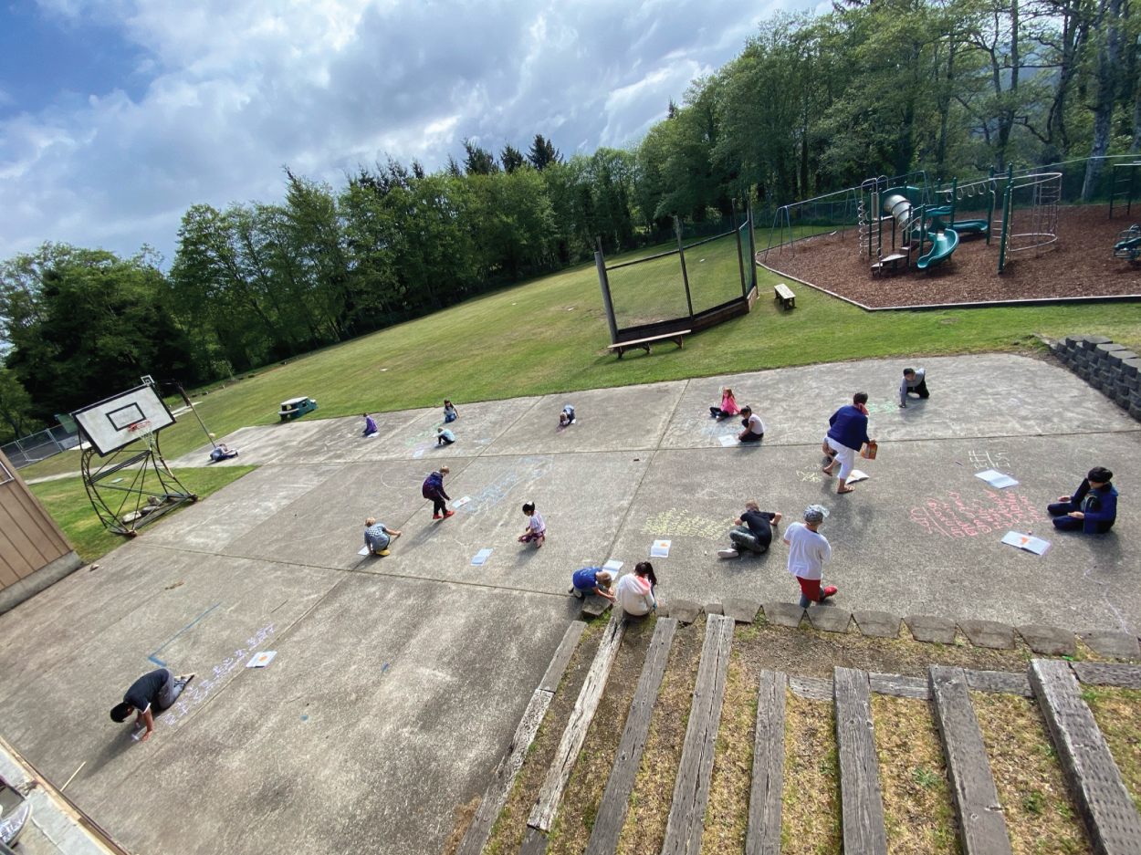 Photo depicts students using chalk in the schoolyard