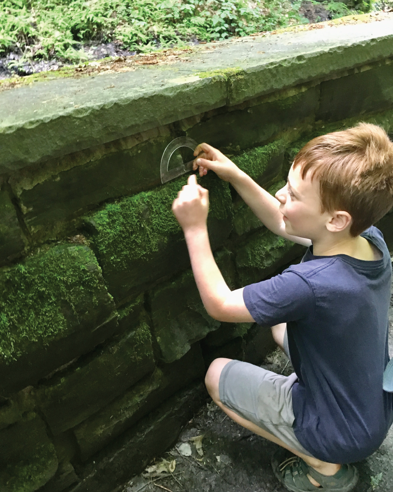 Photo depicts measuring the angles between rocks on a retaining wall