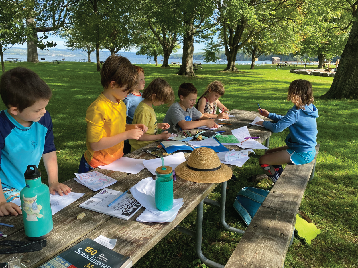 Photo depicts students working on a writing project outdoors.