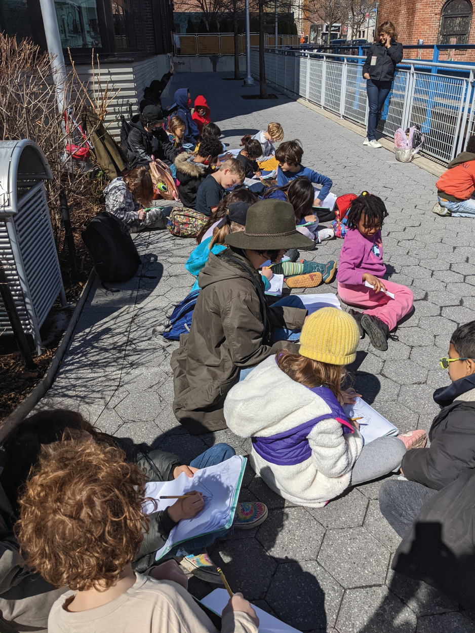 Photo depicts a class working on a project on the sidewalk.