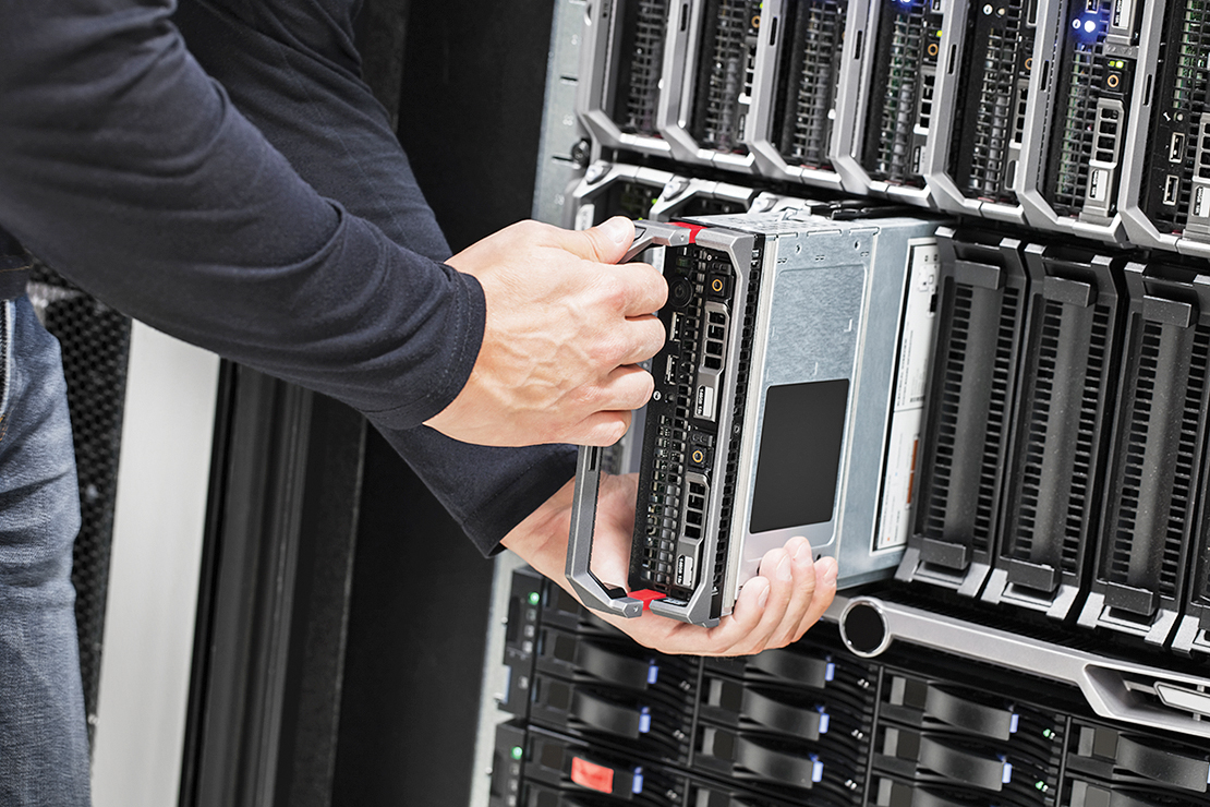 A photo shows a person placing a blade server in a rack full of blade servers.
