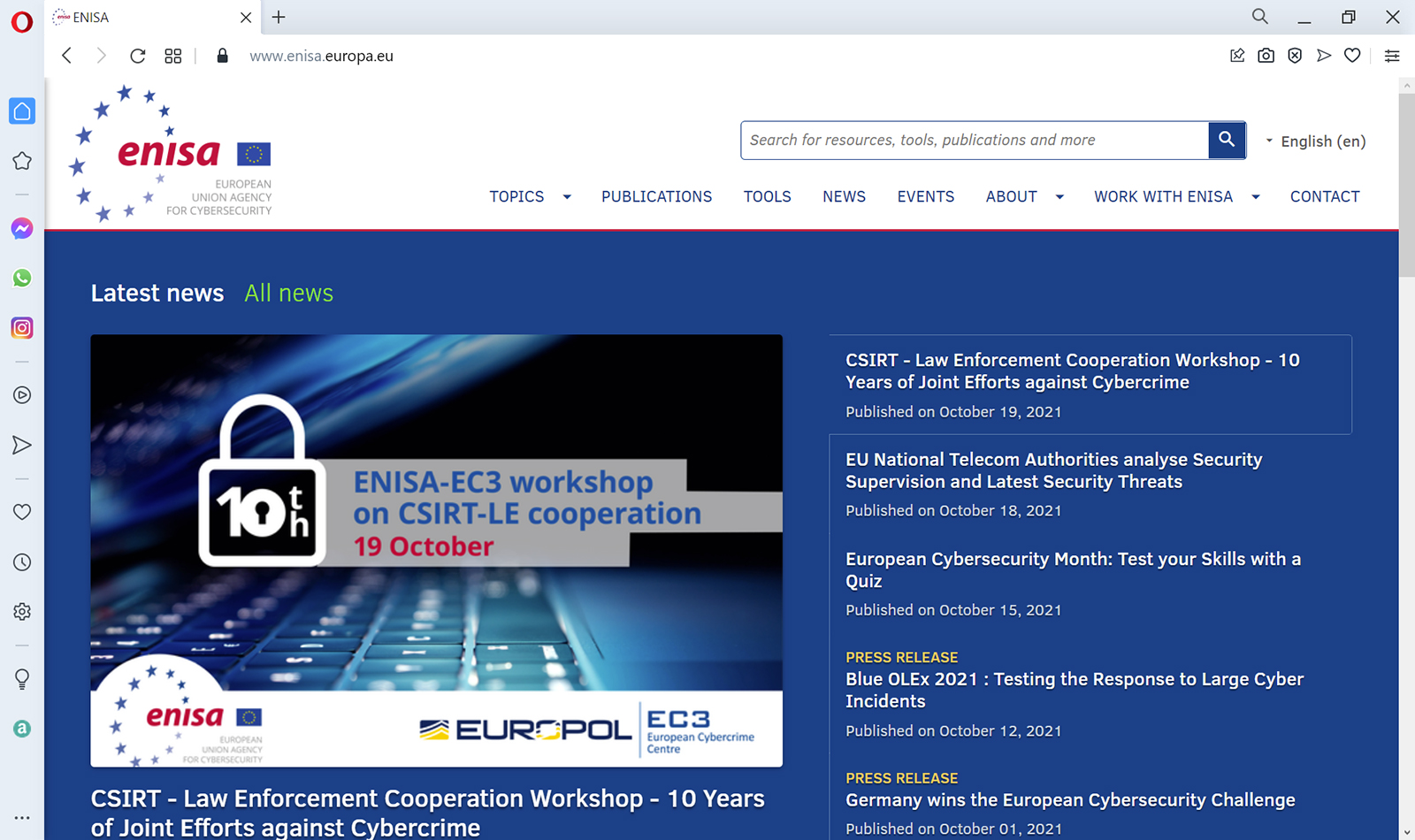 E N I S A European Union agency for cybersecurity is indicated at top left of the page. Topics, Publications, Tools, News, Events, About, Work with E N I S A, and Contact are the menus at the top. Latest news and All news are the options of the content pane in which Latest news is selected. Latest news are listed on the right of the content pane in which the top news, C S I R T Law Enforcement Cooperation Workshop, 10 years of joint efforts against cybercrime, is selected. The news item is displayed on the left.