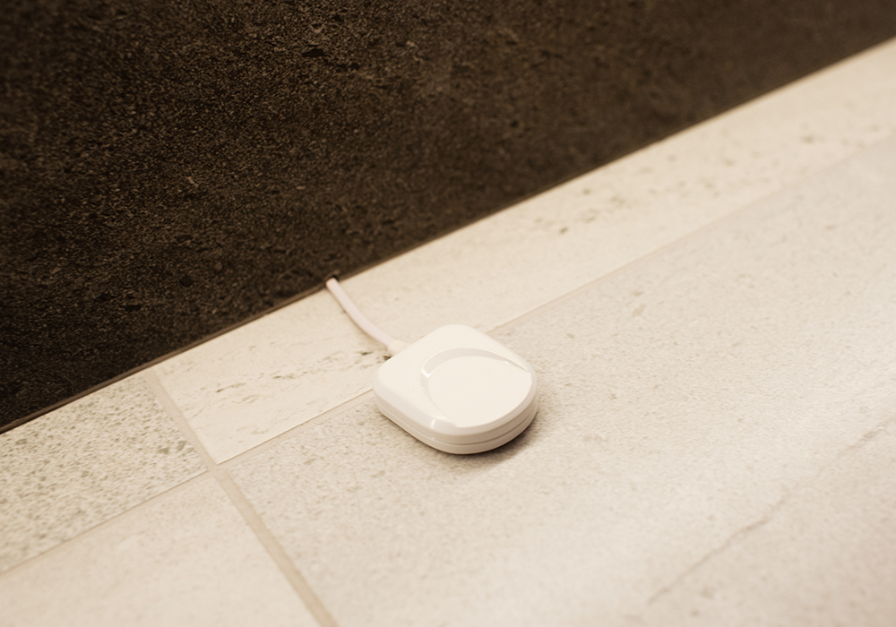 A photo shows a flood sensor placed on the floor and connected with a wire.