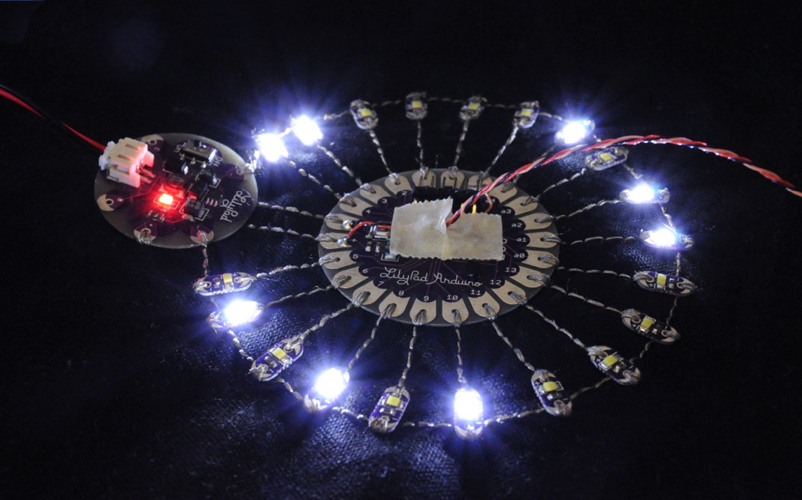 Figure 15.6 – Wearable project using an Arduino Lilypad (courtesy: https://upload.wikimedia.org/wikipedia/commons/e/ea/Lilypad_Arduino_with_fading_LEDs.jpg)
